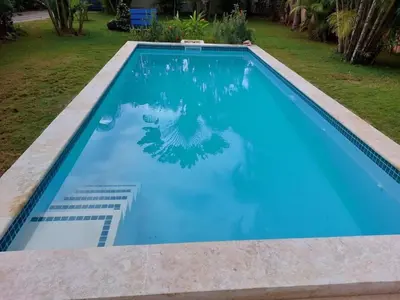 a swimming pool with blue water in a yard at Canela House 3BR Near to the beach in Las Terrenas