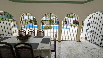 a room with a table and chairs and a pool at Cofresi Villas in Maggiolo