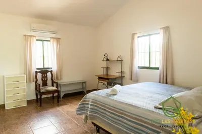 a bedroom with a bed and a chair and windows at Playa Grande House in Las Galeras