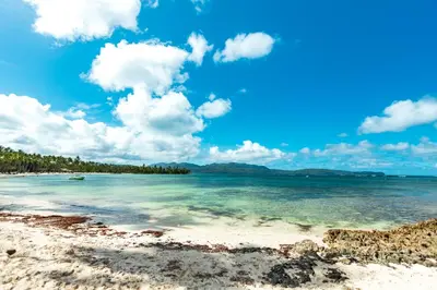 a beach in the ocean with a blue sky and clouds at Playa Grande House in Las Galeras