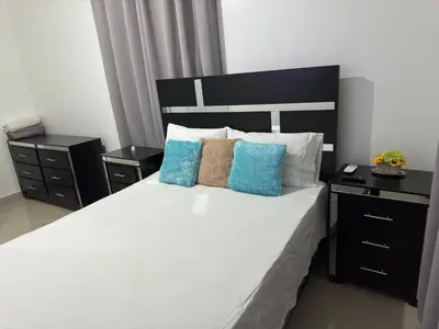 a bedroom with a large white bed with blue pillows at Hermoso Apartamento en 3er nivel con terraza privada in Bonao