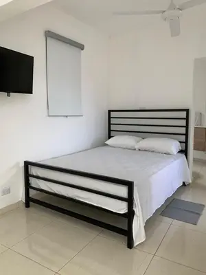 a bed with two pillows and a television in a room at Acogedor apartamento de 1 dormitorio cerca de la playa in Sosúa