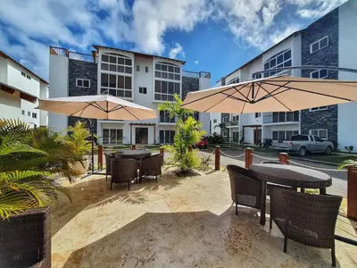 a patio with tables and umbrellas in front of a building at Apartment w private terrace and Jacuzzi in Las Terrenas