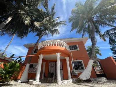 a house with two palm trees in front of it at Cerca de la playa apartamento familiar in Punta Cana