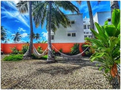a resort with hammocks and palm trees and a building at Cerca de la playa apartamento familiar in Punta Cana