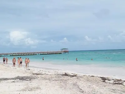 a group of people walking on a beach with a pier at Cerca de la playa apartamento familiar in Punta Cana