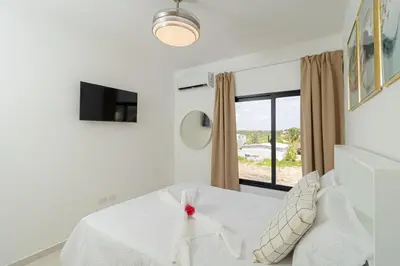 a bedroom with a white bed with a window at Cozy 2BR Apartment in Sunshine Bayahibe in San Rafael del Yuma