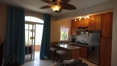 a kitchen with wooden cabinets and a ceiling fan at Juan Dolio Near Beach, Pool Cozy Stay in Villas del Mar