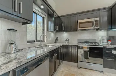 a kitchen with stainless steel appliances and black cabinets at My luxury villa in Sosúa