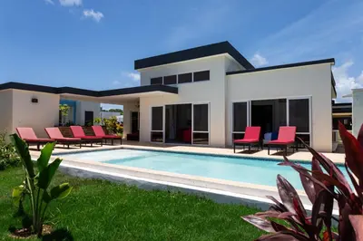 a villa with a swimming pool and red chairs at My luxury villa in Sosúa