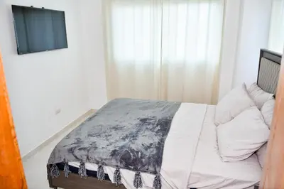 a bedroom with a bed and a tv on a wall at Paraíso encantado Juan Dolio, Confort y Seguridad in Villas del Mar