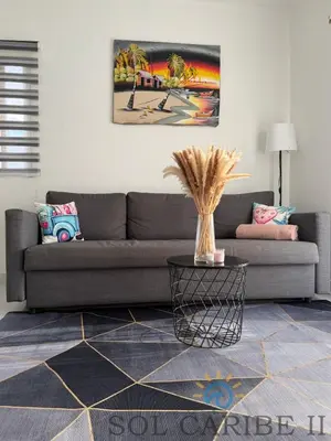 a living room with a gray couch and a table at Bright & Airy Apartment in Bayahibe