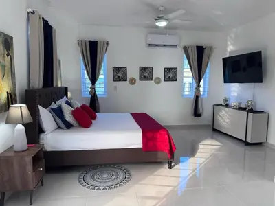 a bedroom with a large bed with red and blue pillows at Villa Tropical Paradise Pool Rooftop in San Felipe de Puerto Plata