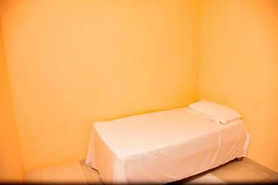 a small bedroom with a white bed in a yellow wall at Boom Ranch in Las Galeras