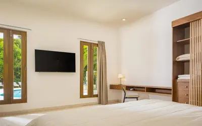 a bedroom with a bed and a tv on a wall at Tropical Roga Villa with Private Pool in Cabarete