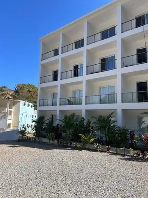 a white building with palm trees in front of it at Refugio Verde Las Terrenas in Las Terrenas