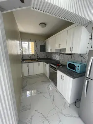 a small kitchen with white cabinets and marble floors at Apartamento 2 in Cancino