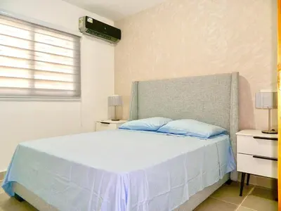 a white bedroom with a bed with blue pillows at The Chic Hideout full apt in san isidro Terrace in Juan López