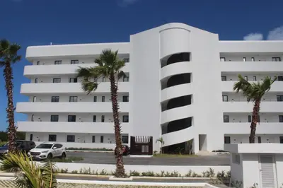a white building with palm trees in front of it at Blue Paradise Punta Cana in Punta Cana