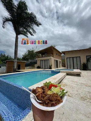 a person holding a plate of food next to a pool at Villas Las Indigenas in Imbert
