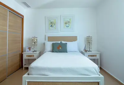 a bedroom with a white bed and two night stands at Condominio Marbella Juan Dolio in Villas del Mar