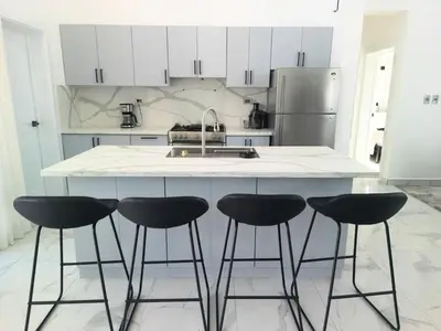 a kitchen with a counter with four bar stools at Modern 3 BR Villa with pool in gated community in Sosúa