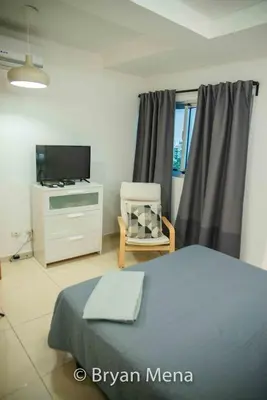 a bedroom with a bed and a tv and a chair at Eclectic gorgeous, modern 3 levels penthouse in Santo Domingo