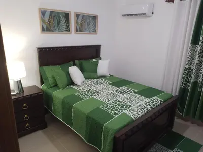 a bedroom with a bed with a green and white comforter at Apartamento Tipo resort-style space in Santiago de los Caballeros