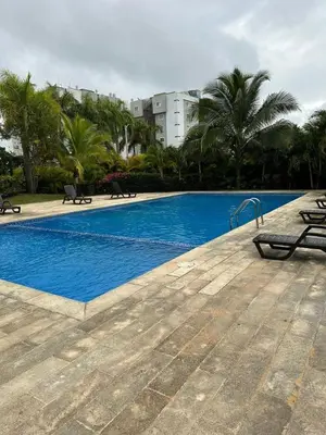 a blue swimming pool with palm trees and a building at Apartamento Tipo resort-style space in Santiago de los Caballeros