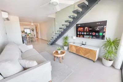 a living room with a white couch and a tv at Corner Penthouse with Ocean and City Views with a Content Creator Hub in Punta Cana