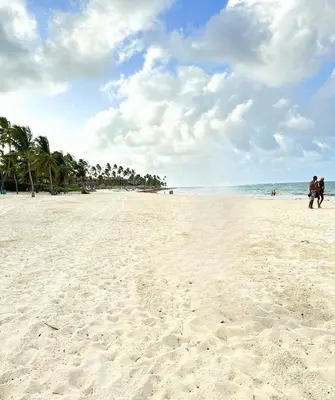 two people walking on a sandy beach near the ocean at Peaceful 2 Bed Apartment - Pool & Private Beach Access in Punta Cana