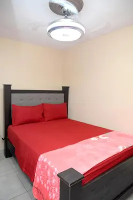 a bedroom with a red bed with a red blanket at HERMOS APARTAMENTo in Santiago de los Caballeros