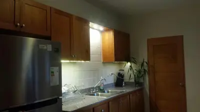 a kitchen with wooden cabinets and a stainless steel refrigerator at Luxury Apartment close to centre of Jarabacoa in Jarabacoa