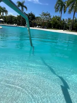 a pool of blue water with a metal rail in it at Beautiful apartment in Playa Dorada in San Felipe de Puerto Plata