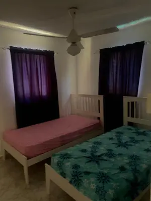 two beds in a room with purple curtains and a bed at Casa modesta para disfrutar in Colorado
