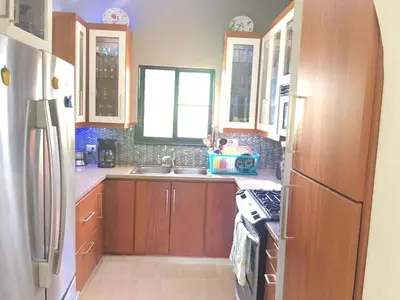 a kitchen with wooden cabinets and a sink and a refrigerator at Villa vacances de reve in Sosúa