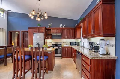 a kitchen with wooden cabinets and a island with bar stools at Casa Linda Villa 722 - Sosua - BBQ - Washer in Sosúa
