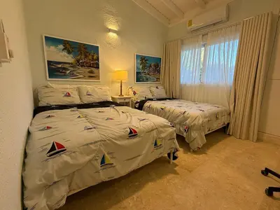 a hotel room with two beds and a window at Juan Dolio House 2BR y Patio in Los Corrales