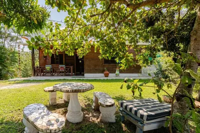 a garden with a table and benches in front of a house at La Casita Primavera-Cozy and Rustic in Piedra Blanca