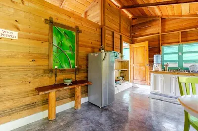 a kitchen with a refrigerator in a wooden wall at La Casita Primavera-Cozy and Rustic in Piedra Blanca
