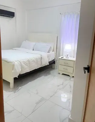a white bedroom with a bed and a white tiled floor at Villa súper cómoda 3 habitaciones con piscina in Juan López
