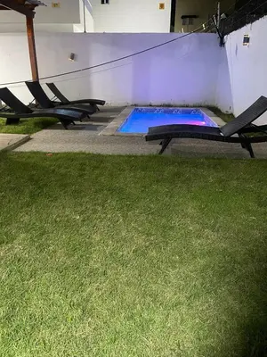 a swimming pool with two chairs in a yard at Villa súper cómoda 3 habitaciones con piscina in Juan López