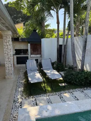 two chairs and a fireplace in a backyard with palm trees at 2BR Juan Dolió House in Juan Dolio
