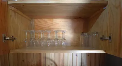 a wooden cabinet with glasses on a shelf at La Casita De La Cueva in Cabo Rojo