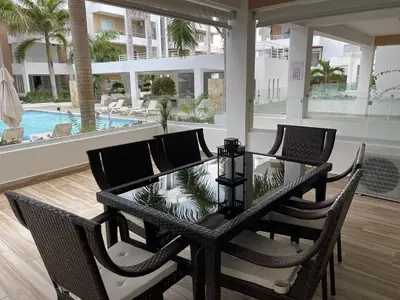 a dining room table with four chairs and a pool at Sweet Home Bayahibe in Bayahibe