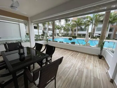 a living room with a table and a swimming pool at Sweet Home Bayahibe in Bayahibe