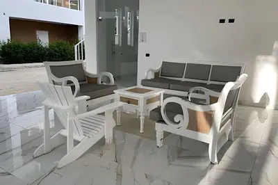 a patio with white chairs and a table and a couch at Sweet Home Bayahibe in Bayahibe