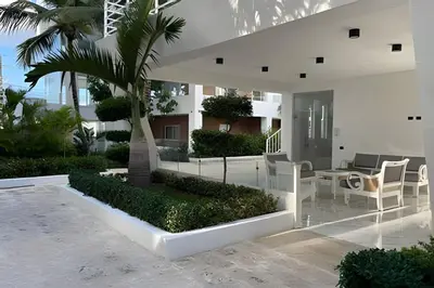 a white house with a palm tree and a patio at Sweet Home Bayahibe in Bayahibe