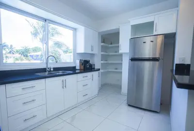 a kitchen with white cabinets and a stainless steel refrigerator at Sosua Residence by CJDR in Sosúa