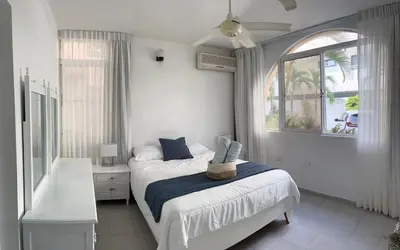 a white bedroom with a bed and a window at Villas Princesa Beach Apartments in Punta Cana